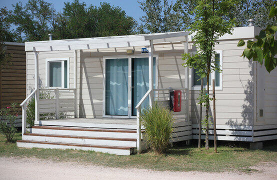 Luxury mobile homes with terraces in a four-star campsite near Rimini, Italy, surrounded by landscaped gardens and trees. Modern camping accommodation on the Adriatic coast in Italy, Europe.