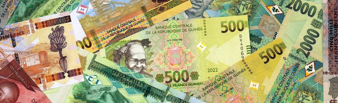 Guinean franc money bills in pile on table. Guinea GNF currency cash close up