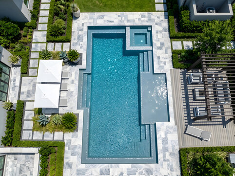 Luxury backyard swimming pool design with pebble finish | Modern pool patio landscape with marble pavers | Aerial view of contemporary residential pool and spa area | High-end outdoor living space