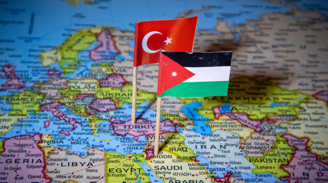 Turkey and Jordan flag pins on world map symbolizing bilateral relations and travel.