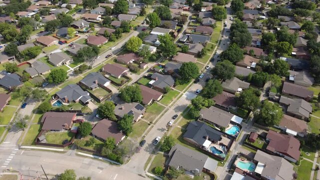Avenues intersect near Lyons Crest Estates in DFW metroplex. Inground backyard pools, timber privacy fences, detached storage sheds border single family homes along cul de sacs, Garland, Texas
