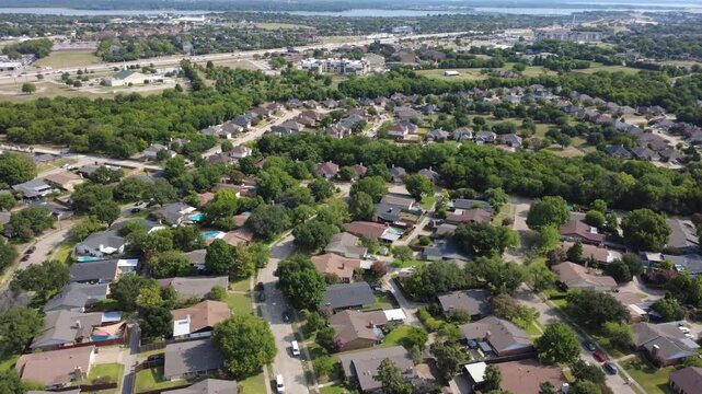 Single family home rooflines spread through Lyons Crest Estates in Dallas Fort Worth suburbs near major highways. woodland buffers separate housing blocks from surrounding pastures, Garland, TX