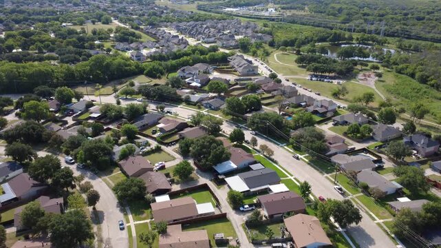 Single family brick homes line curved residential avenues in Lyons Crest Estates in DFW metroplex. Timber privacy fences separate neat backyards, driveway entrances, front yard trees, Garland, TX