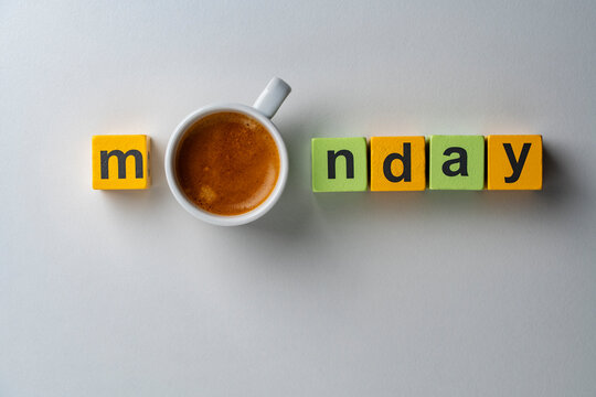 Monday morning concept with cup of coffee and wooden toy blocks, closeup. Top view of the word monday spelled with colorful wooden cubes and cup of fresh espresso replacing the letter o