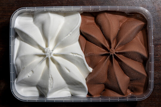 Top view of chocolate and vanilla ice cream container, closeup. Plastic container filled with half white vanilla and half brown chocolate ice cream styled in beautiful star shapes