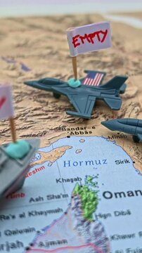 Miniature US army vehicles with empty flags over a map of Iran and the Strait of Hormuz, representing a conceptual military stockpile crisis, arms shortage, and geopolitical tension