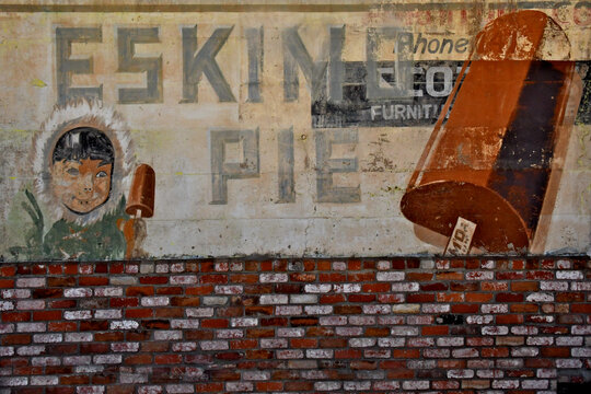 Brick wainscoting partially covers old Eskimo Pie ghost sign considered insensitive today because the term "Eskimo" is a colonial, non-Indigenous descriptor, Jamestown, California. Edy's Pie today