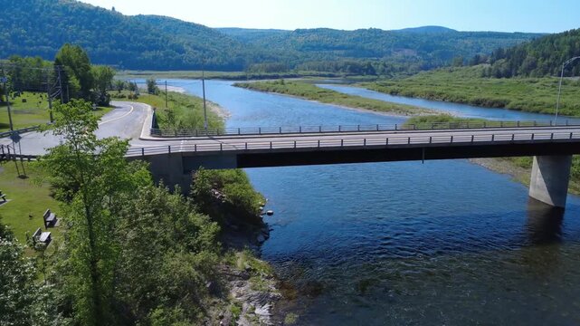 Cinematic drone footage flying under a road bridge on the Matapedia River, facing the spectacular Appalachian landscape of Quebec. Canada.