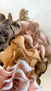 Close-up of elegant artificial floral arrangement in soft pink, beige, brown and gold tones on a light marble surface with copy space. Decorative flowers for modern home interior styling.