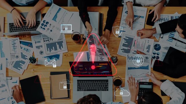 A dynamic team engages in collaborative efforts around a table, analyzing data and strategizing, with digital warning symbols highlighting critical information. Raster