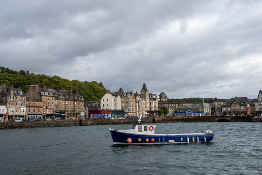 View into land of a Fishing boat sailing into Oban harbour on an overcast day, Argyll & Bute, Scotland, UK