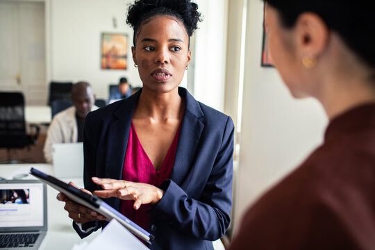 Businesswoman discussing project with colleague in modern office
