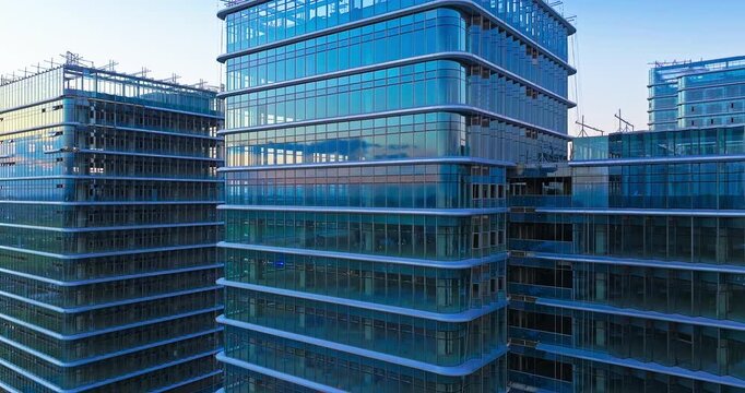 Contemporary glass office complex with reflective blue facades and active construction details, showcasing modern urban architecture and commercial property development.