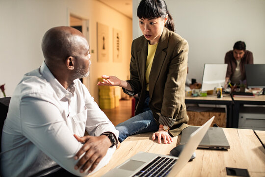 Coworkers discussing project at modern open office desk