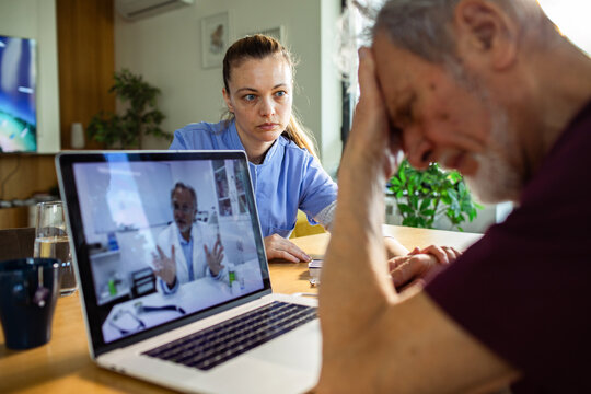 Nurse with stressed senior during online doctor consultation at home