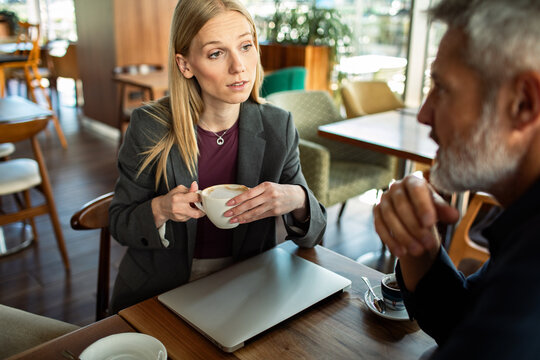 Two professionals discussing work over coffee in a cafe