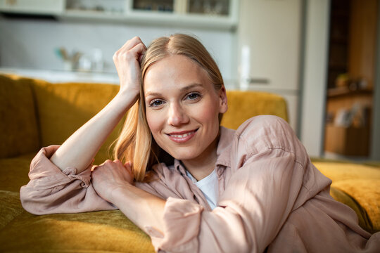 Smiling young woman relaxing on sofa at home