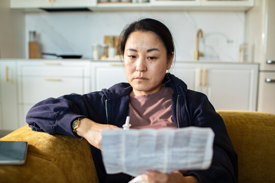 Concerned woman reading medication instructions in home kitchen