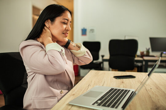 Businesswoman massaging sore neck at office desk