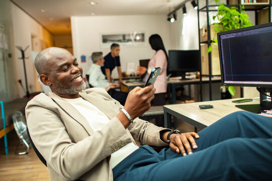 Smiling professional using smartphone at desk in modern open office