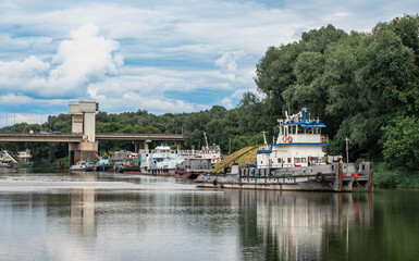 Fototapeta premium Push Tugboat Moored on River Near Bridge and Forest Bank
