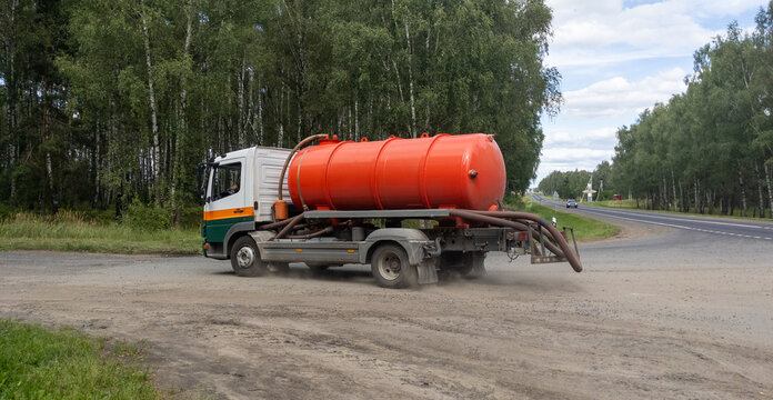 Sewage truck turns onto the road to a farm. Vacuum truck for wastewater treatment. Waste distribution and utilization policy concept.
