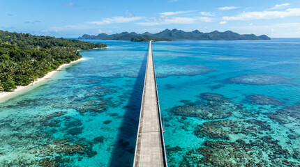 Fototapeta premium High-altitude drone shot of a long straight coastal highway bridge crossing over a shallow crystal clear turquoise ocean, vibrant coral reefs visible underwater, tropical paradise travel vibe, bright 