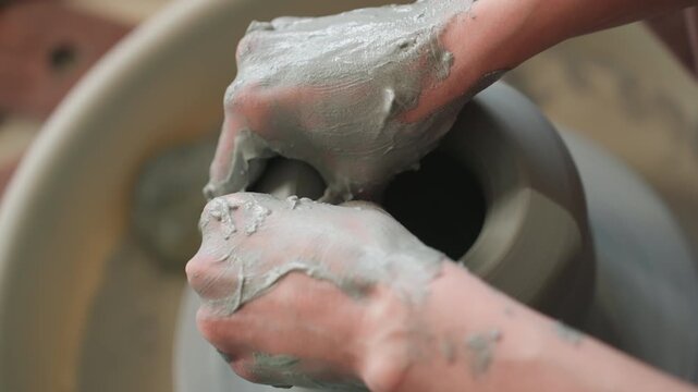 Artisan meticulously refining clay on pottery wheel. Master sculptor carefully hollowing and detailing ceramic vessel. Skilled craftsman adding final touches to handmade clay vase in studio setting