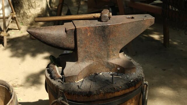 A heavy metal anvil with a hammer sitting on top, suitable for construction or industrial scenes