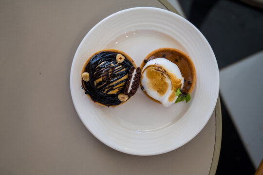 Chocolate and caramel tart desserts on white plate, top view