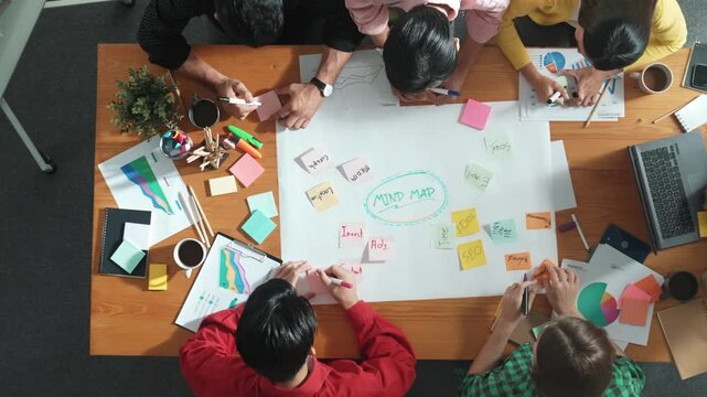 Group of business people writing and making mind map to brainstorming marketing idea at meeting. Top aerial view of investors sharing plan or strategy by using sticky notes. Time lapse. Convocation.