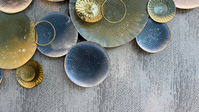 Abstract metallic wall decoration with overlapping textured circles in blue, gold and gray tones on a patterned wall, modern luxury interior design with copy space.