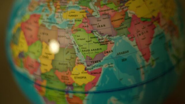 Colorful globe spins slowly, highlighting Middle East nations. Soft light glows on globe's surface, creating gentle reflections. Close-up emphasizes detailed map, with clear borders and names
