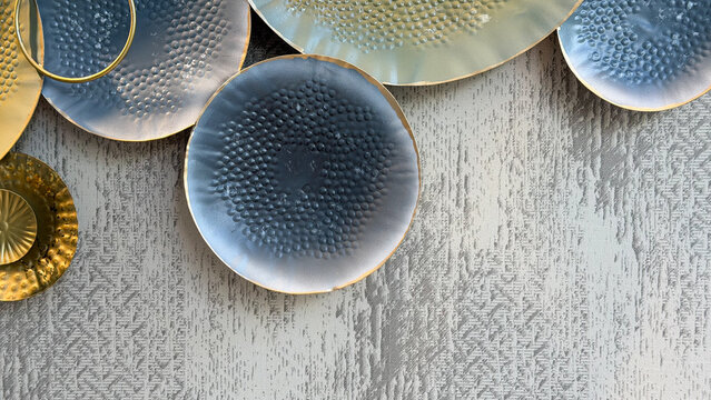 Abstract metallic wall decoration with overlapping textured circles in blue, gold and gray tones on a patterned wall, modern luxury interior design with copy space.