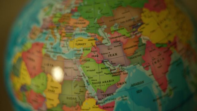Globe spins slowly, highlighting Iran and surrounding nations. Colorful map details stand out with soft focus effects. Ideal for travel, geography, or global awareness themes