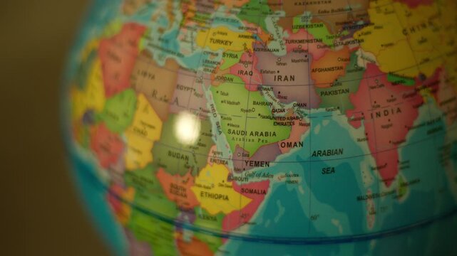 Close-up globe spinning over Middle East and Africa region. Colorful map shows continents with clear country names. Bright spot reflects off globe's glossy surface