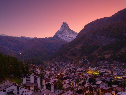 Sunset view over the town of Zermatt with Matterhorn mountain in the background. Evening light illuminates Swiss alpine village and peak.