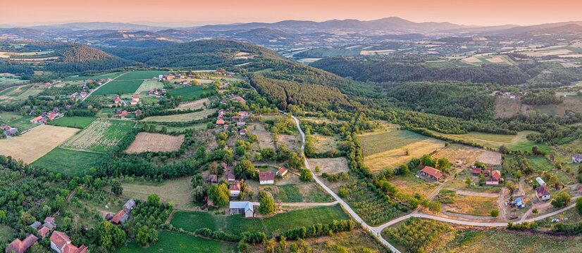 Aerial panoramic view of a patchwork rural landscape with farmland and scattered village houses. Countryside concept.