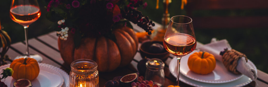 Banner. Beautiful elegant autumn table setting for thanksgiving family dinner or wedding. Pumpkin with flowers as centrepiece. Cozy fall home atmosphere. Wineglass, romantic marriage proposal, sunset