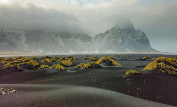 Vestrahorn mountain overlooking black volcanic sand dunes with grassy mounds on stokksnes beach at sunset. Iceland, icelandic landscape