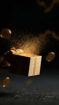 Gold gift box surrounded by shimmering coins on a dark background.