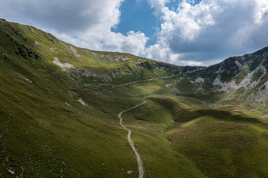 Aerial view of winding mountain trail through green alpine cirque - Bernese Oberland highland landscape, Switzerland