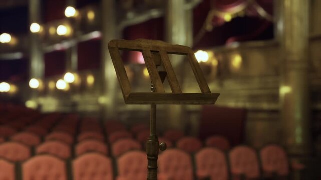 Performer vantage point over empty red house, music stand foreground with layered balconies and plush seating fading into warm lights, charged silence