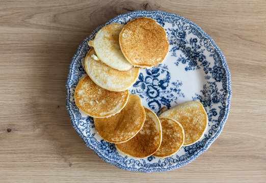 Pancakes stacked on a blue floral plate on a wooden table