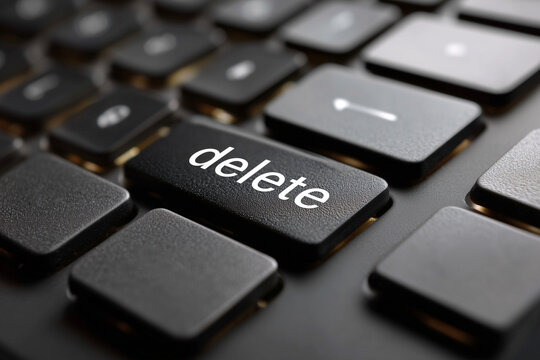 Black computer keyboard with focus on the delete key close up view. Modern plastic laptop keypad button for removing data and text correction. Technology conceptual background
