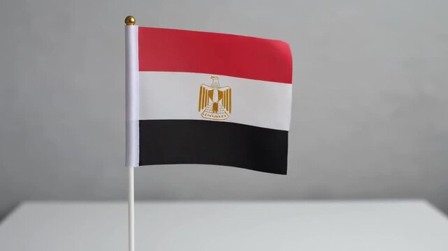 Small Egypt Flag Waving on White Table Desk Stand Isolated on Grey Background