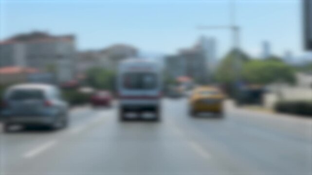 A blurred daytime video following an emergency ambulance driving fast through city traffic, capturing a fast paced sense of urgency and motion blur during a rescue response