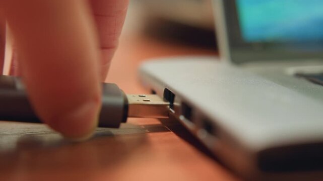 Closeup laptop port and usb cable content creator preparing to import footage, gentle fingertip guide during careful insert, studio evening light, tactile setup with shallow focus and soft bokeh