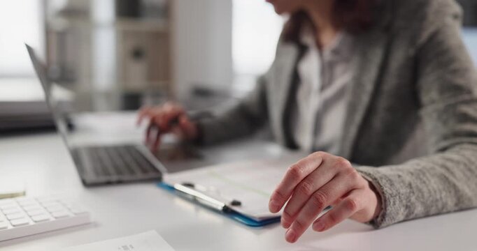 Woman hands reviewing paperwork near laptop. Manager uses computer, typing to check figures on clipboard, focusing on accuracy, data entry and order at workplace. Concept of exact office work.