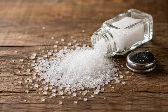 Coarse Salt Spilled from Glass Shaker on Rustic Wooden Table